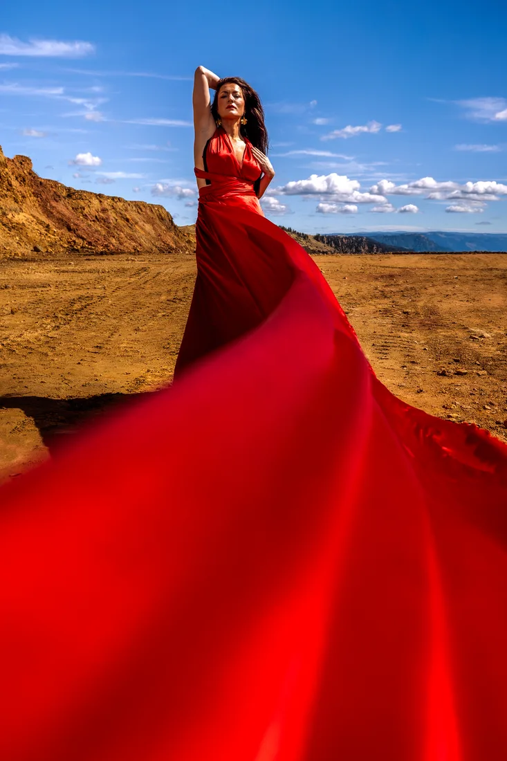 Woman in a red gown in a quarry, the dress train filling the foreground toward the camera